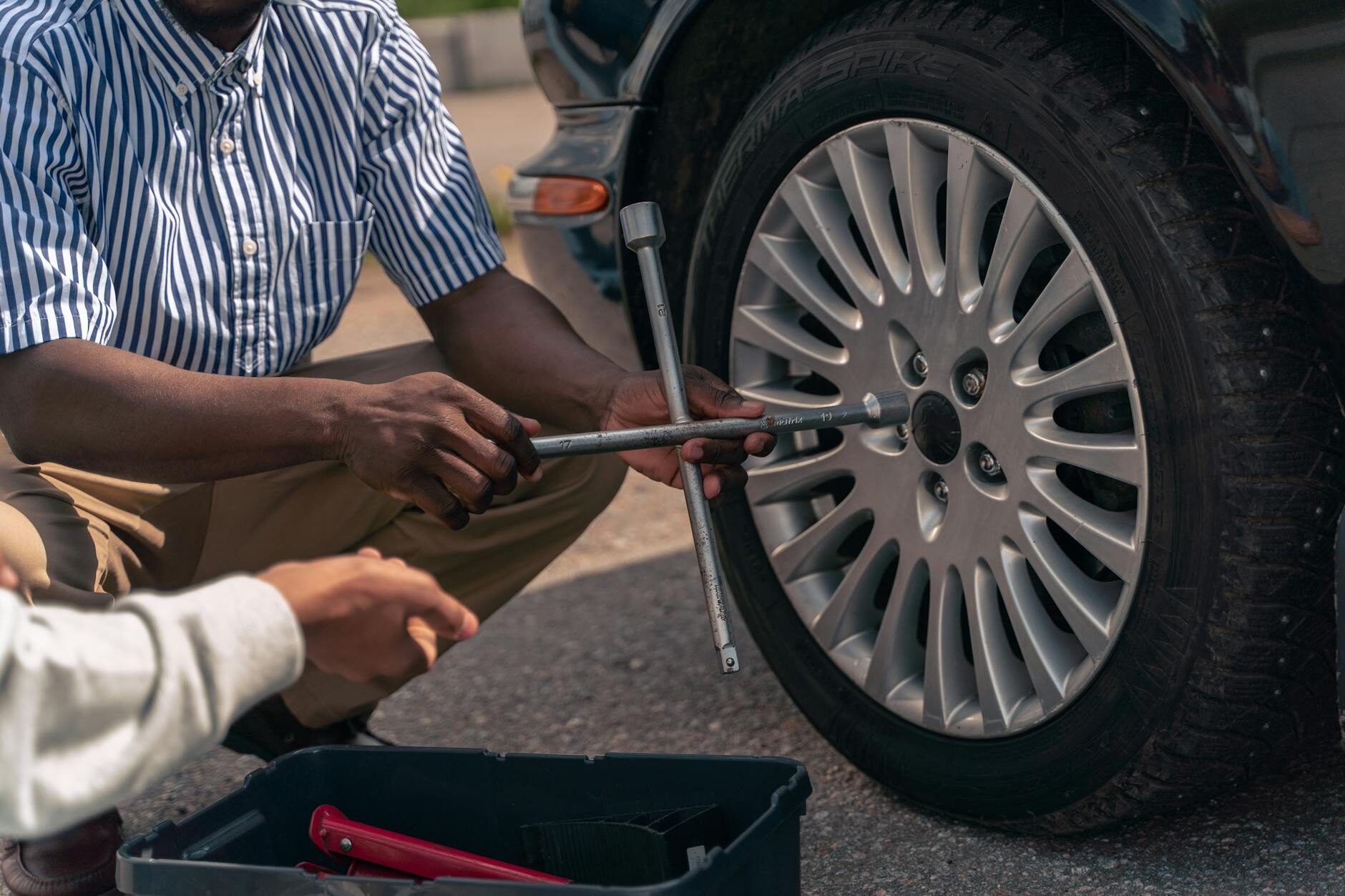 Person holding a black aftermarket wheel, representing the wheel and rim selection at Charleston Tires